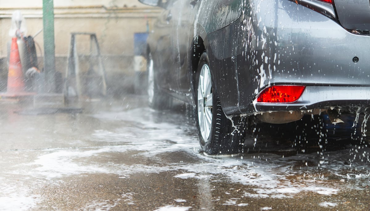 A sedan being thoroughly cleaned with water and soap at a car wash station.