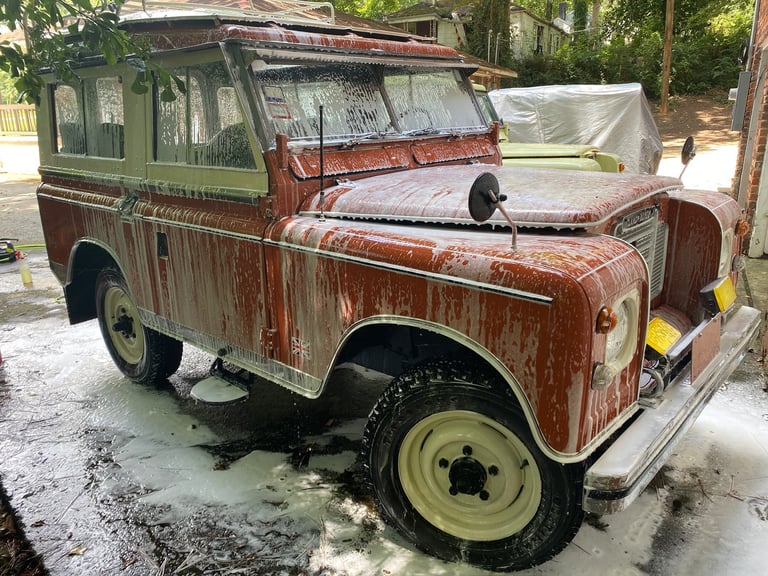 Weathered vintage Land Rover Series truck with rusted red and green body panels