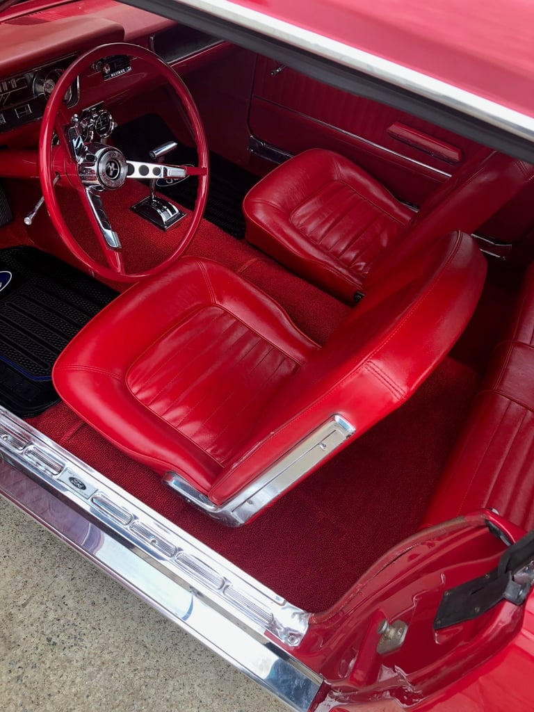 Interior view of a classic red car with red leather bucket seats
