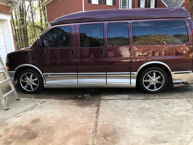 Burgundy minivan with chrome trim parked on concrete driveway