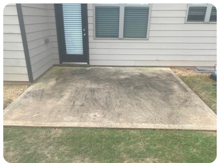 Concrete patio pad in front of white house with black door and windows